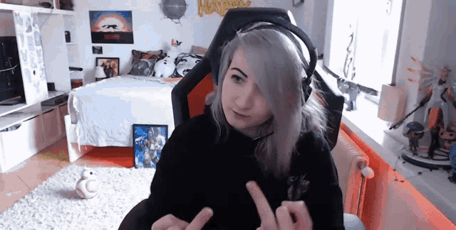 a woman wearing headphones giving the middle finger in a bedroom
