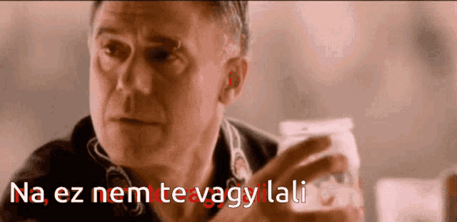 a man holding a jar with the words na ez nem te vagy lali written in red
