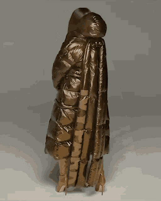 a woman wearing a long brown coat with a hood and boots with the letter n on them