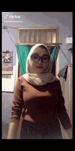 a tiktok video of a woman wearing a hijab and glasses ..