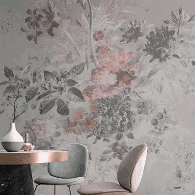 a living room with a chair and a table in front of a pink wall with flowers on it