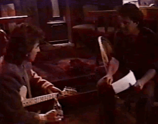 a man singing into a microphone while another man playing a guitar