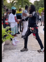 a man with dreadlocks is standing in front of a crowd holding a microphone .