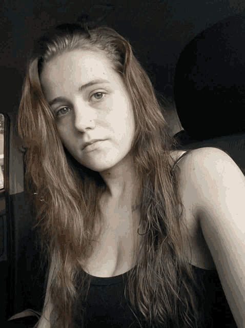 a woman in a black tank top is taking a selfie