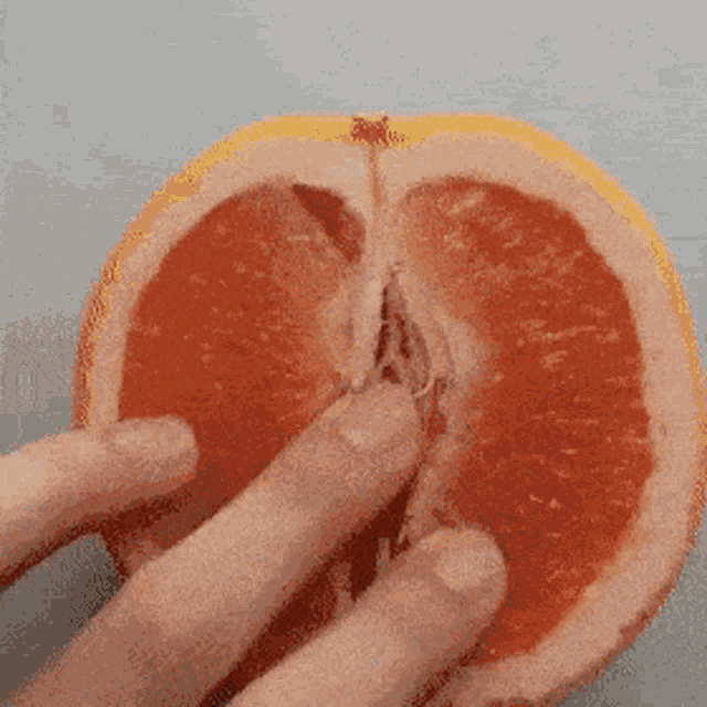 a person is holding a grapefruit with their finger in it