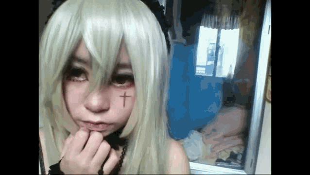 a girl with blonde hair and a cross on her forehead