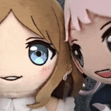 two stuffed dolls are standing next to each other .