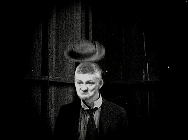 a man in a suit has a hat on his head in a black and white photo