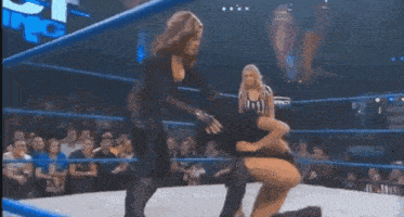 a woman is kneeling down in a wrestling ring with a sign that says impact on it
