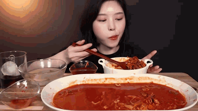 a woman is eating a bowl of sauce with a wooden spoon .