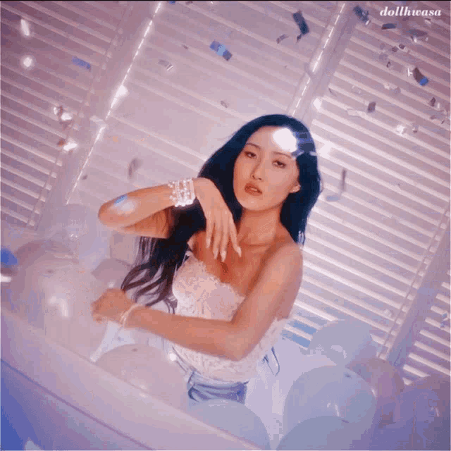 a woman in a white lace top is sitting in front of a window