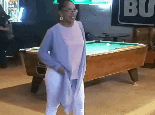 a woman is standing in front of a pool table with a budweiser sign in the background