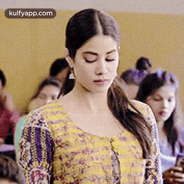 a woman in a yellow and purple dress is standing in front of a crowd of people .