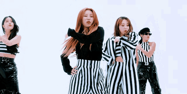 a group of women in black and white striped outfits are dancing .