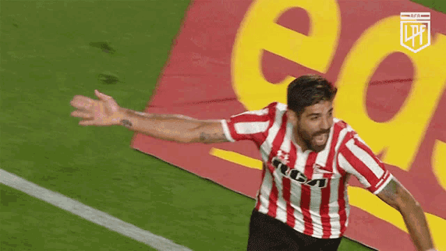 a soccer player in a red and white striped shirt celebrates his goal