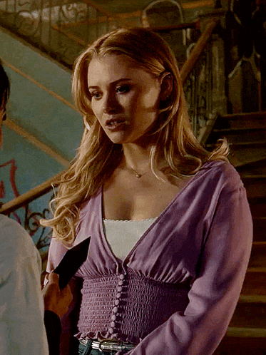 a woman in a purple sweater is standing next to a man in a white shirt