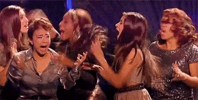 a group of women are standing next to each other on a stage and one of them is crying .