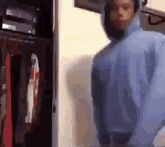 a man wearing a blue hoodie is standing in front of a microwave oven .