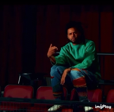 a man in a green sweater is sitting in the stands of a theater .