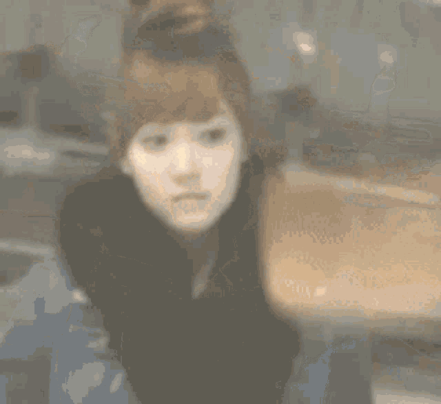 a blurry picture of a woman sitting in a car looking at something .