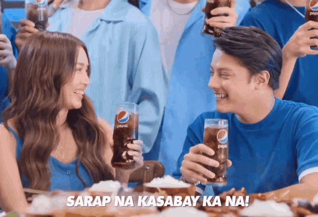 a man and a woman holding pepsi glasses in front of a crowd