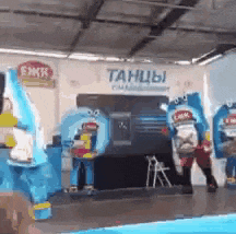 a group of mascots are dancing in front of a sign that says танцы