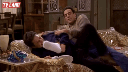 two men are laying on a couch and one of them is wearing a pair of socks .