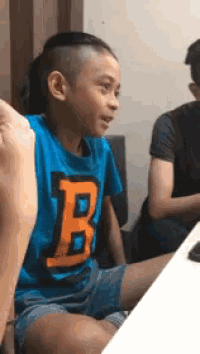 a young boy in a blue shirt with the letter b on it