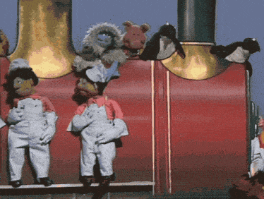 a group of stuffed animals are sitting on top of a red wall