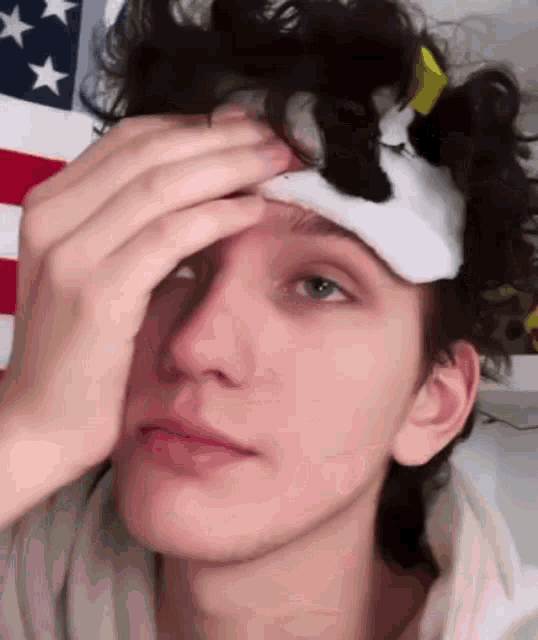 a young man with a bandage on his forehead is holding his forehead .