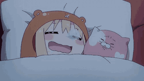 a girl in a bear hat is laying in bed with a pink cat pillow