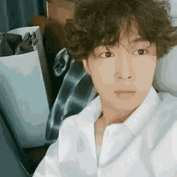 a young man with curly hair is taking a selfie with his phone .
