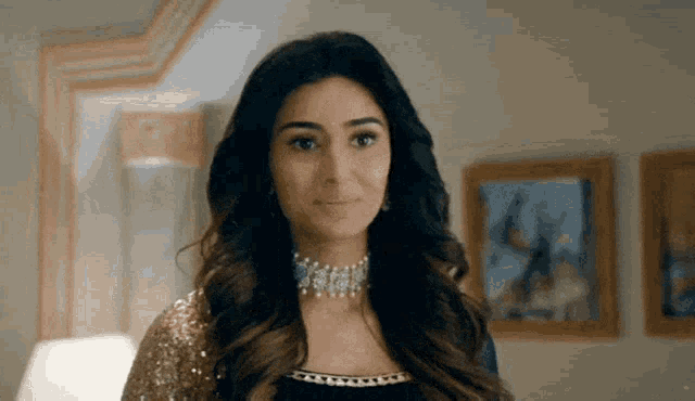 a woman wearing a choker and earrings is standing in front of a wall with paintings .