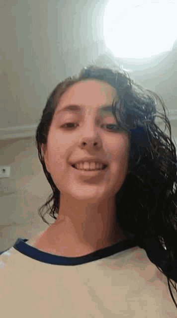 a woman with long curly hair is smiling for the camera