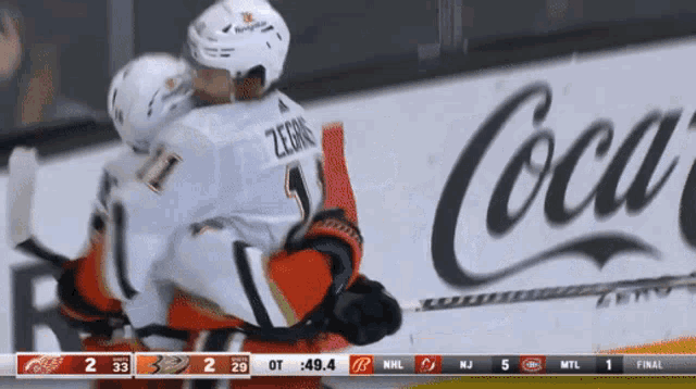 a hockey game is being played in front of a coca cola ad