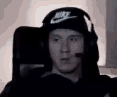 a man is wearing headphones and a hat while sitting in a chair .