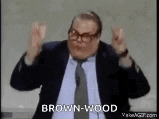 a man in a suit and tie is making a funny face and saying brown wood .
