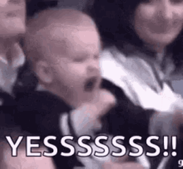 a baby is crying while being held by a woman in a crowd .