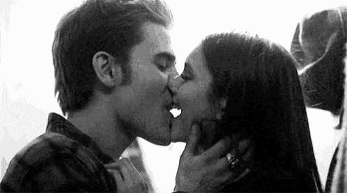 a man and a woman are kissing each other in a black and white photo .