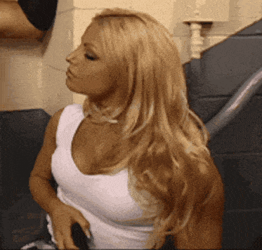 a woman with blonde hair is wearing a white tank top