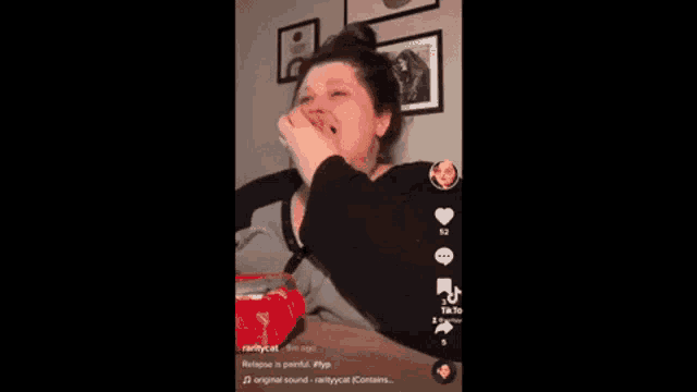 a woman is crying while eating a bag of chips on a tik tok video .