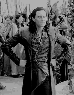 a black and white photo of a man in a leather coat standing in front of a crowd of people .
