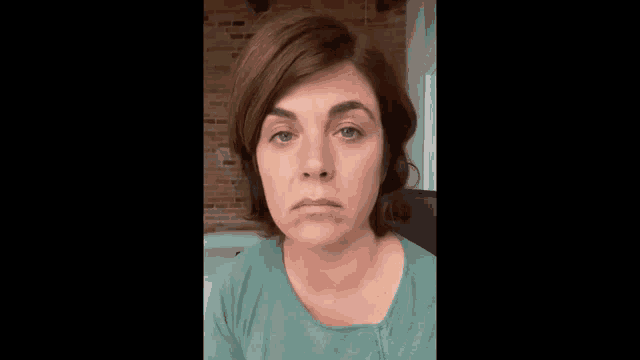 a woman in a green shirt is making a sad face .
