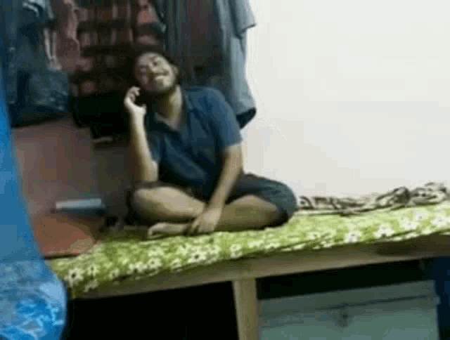 a person is sitting on a bed talking on a cell phone .