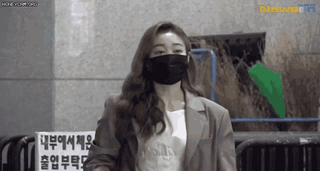 a woman wearing a black mask is standing in front of a sign that says news
