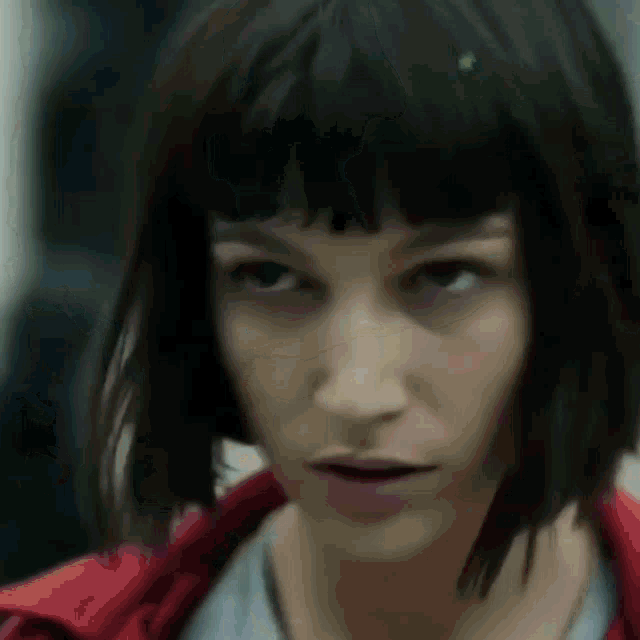 a close up of a woman 's face with short hair and bangs .