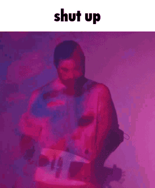 a man is standing in front of a purple and pink background with the words shut up below him