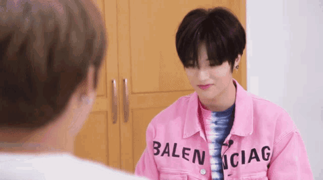 a young man wearing a pink jacket that says balenciag