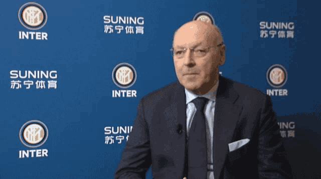 a man in a suit and tie stands in front of a wall that says suning inter