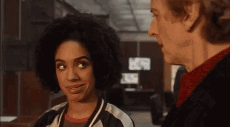 a man and a woman are standing next to each other in an office and looking at each other .